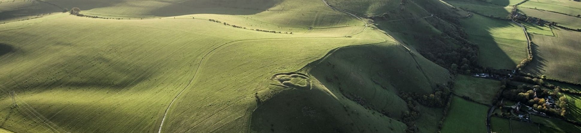 Aerial photo of the South Downs. A circular earthwork can be seen on a prominent ridge.
