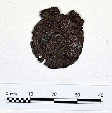 This copper alloy disk with a stamped design was found at Brooke House. Only partial remains of an inscription can be seen around the circumference. It is likely this was lost by a patient or a member of staff.