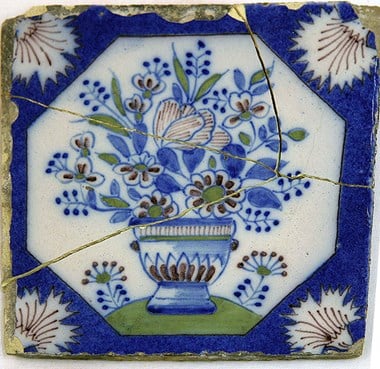 Removed from Brooke House, this polychrome tin glazed Delft tile is decorated with carnations and a bowl of flowers. 