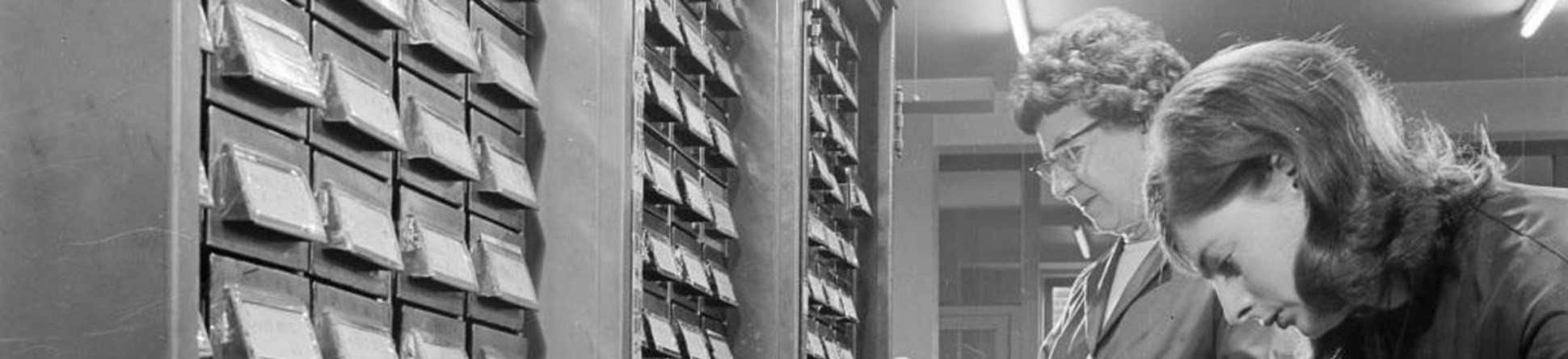Women using the large card index cabinet in the premises of the medical mailing company in Ealing, 1960 - 1970
