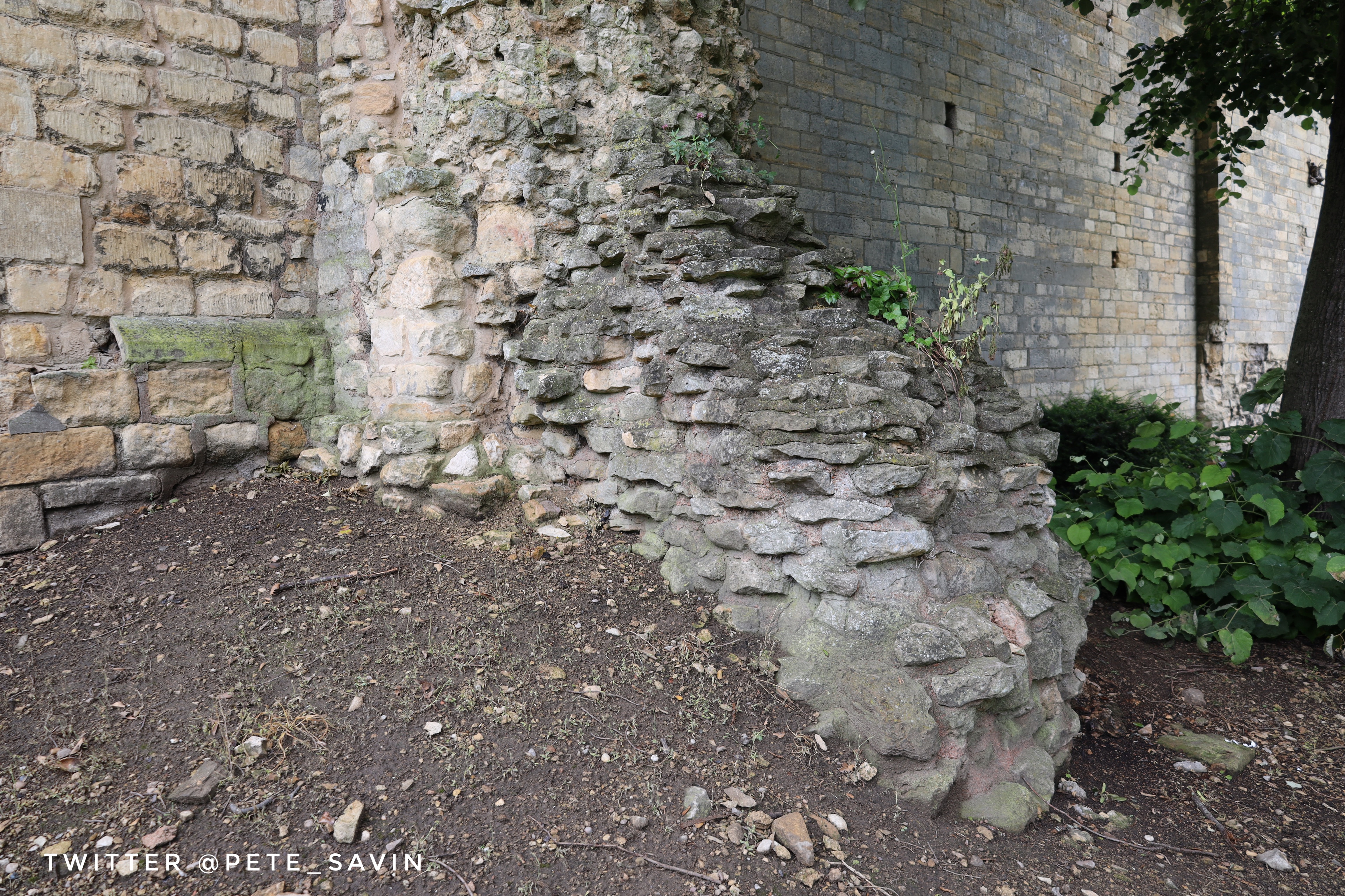 A small section of roman wall projecting out at 90° from a later medieval high wall around the bishops palace 