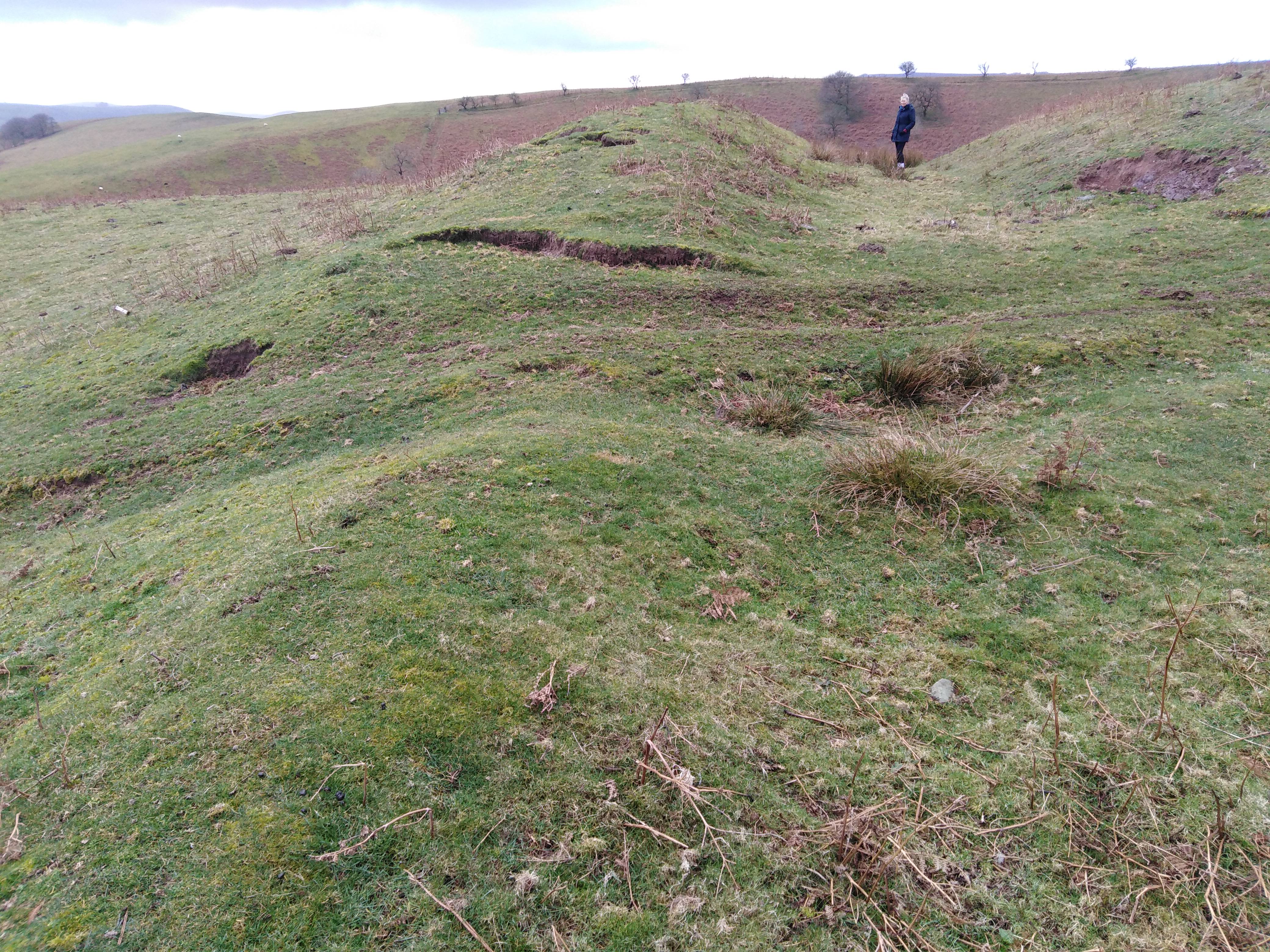 Uphill side defensive bank and ditch. Person in the photo is 6ft, so the ditch is still a significant size.