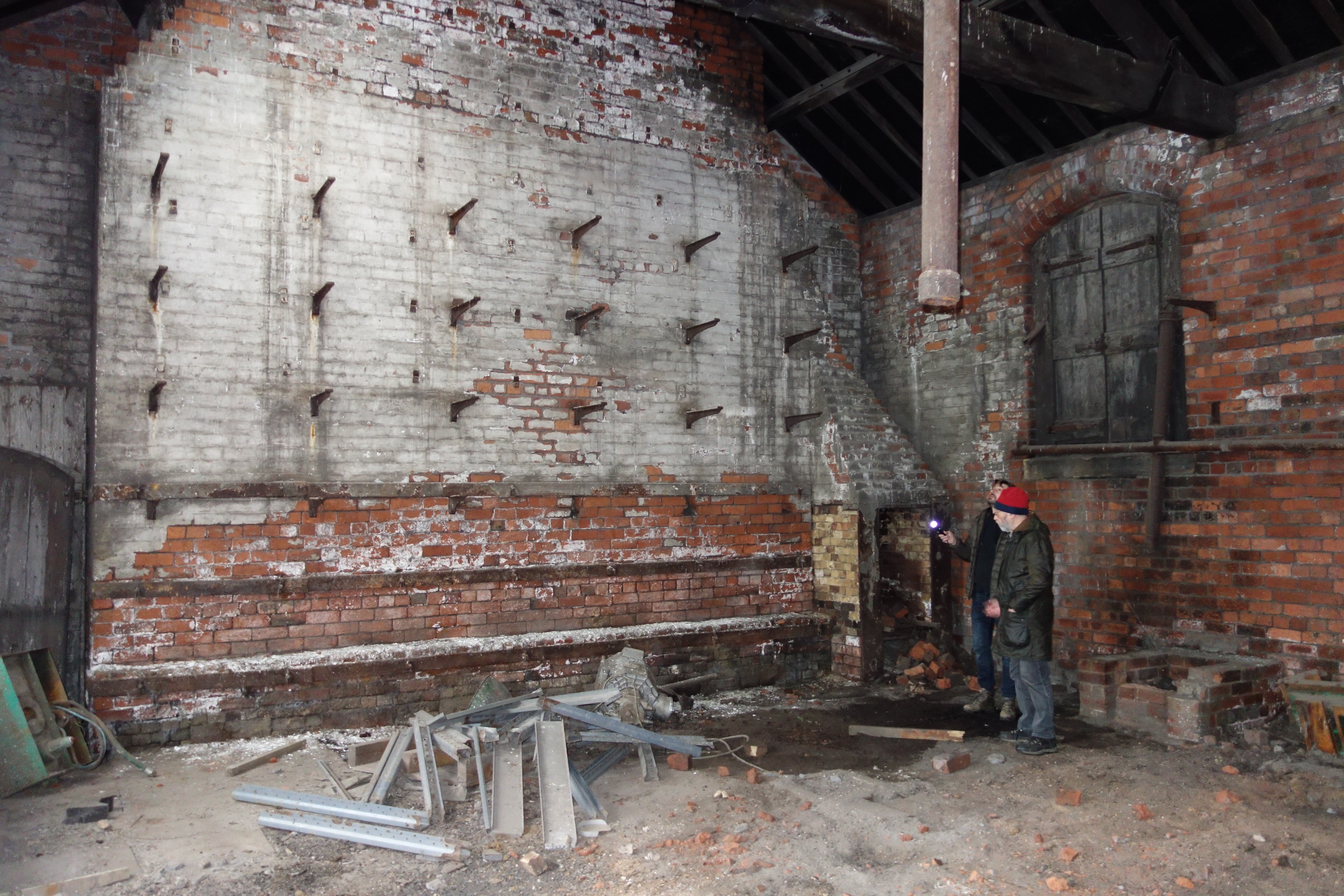 Brick wall of a disused workshop, with four rows of brackets.