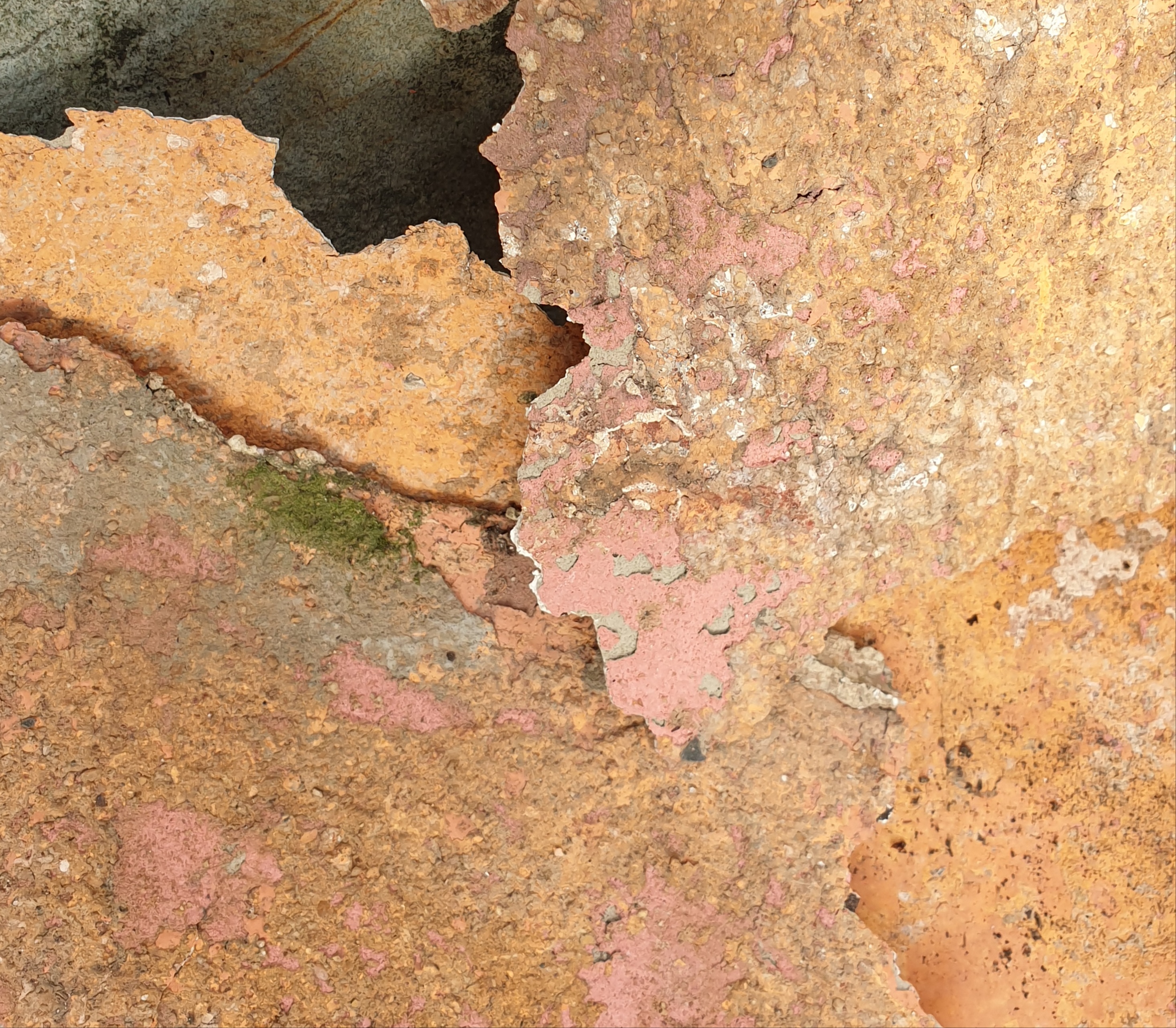 Picture of the flaked off Stucco showing the original Fuscia and laterly orange paint. More evidence found around window