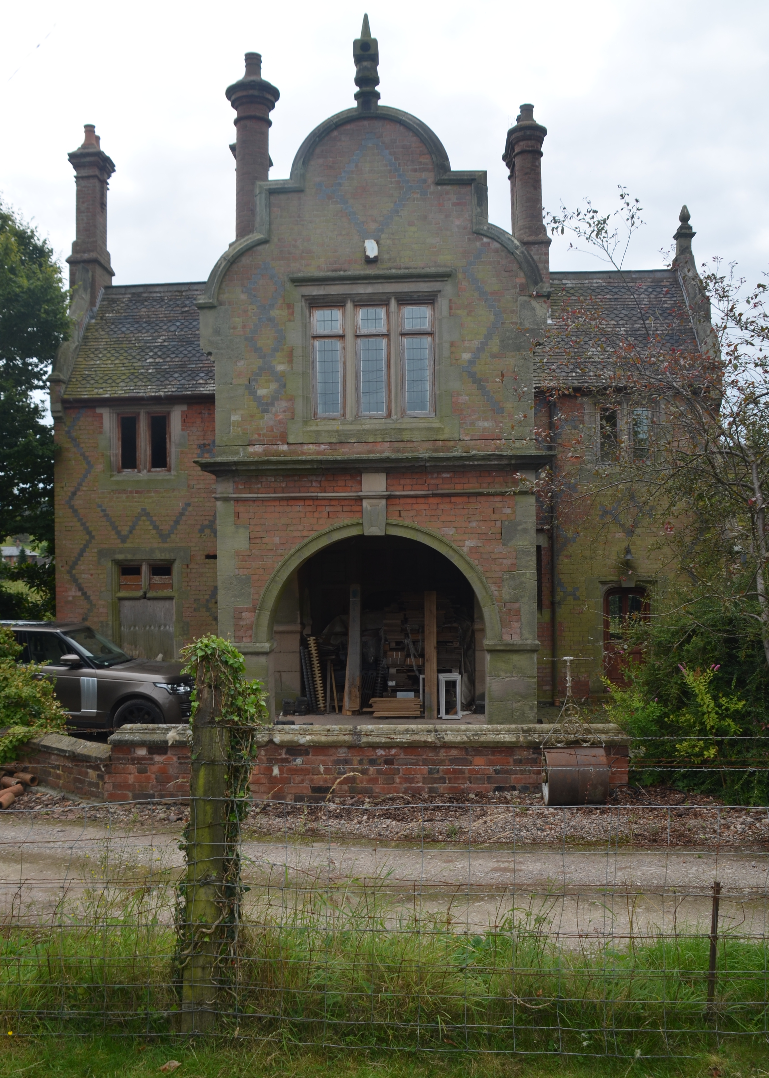 A Jacobean-style building with tall chimney stacks. A fence post to the right marks the boundary of the property grounds