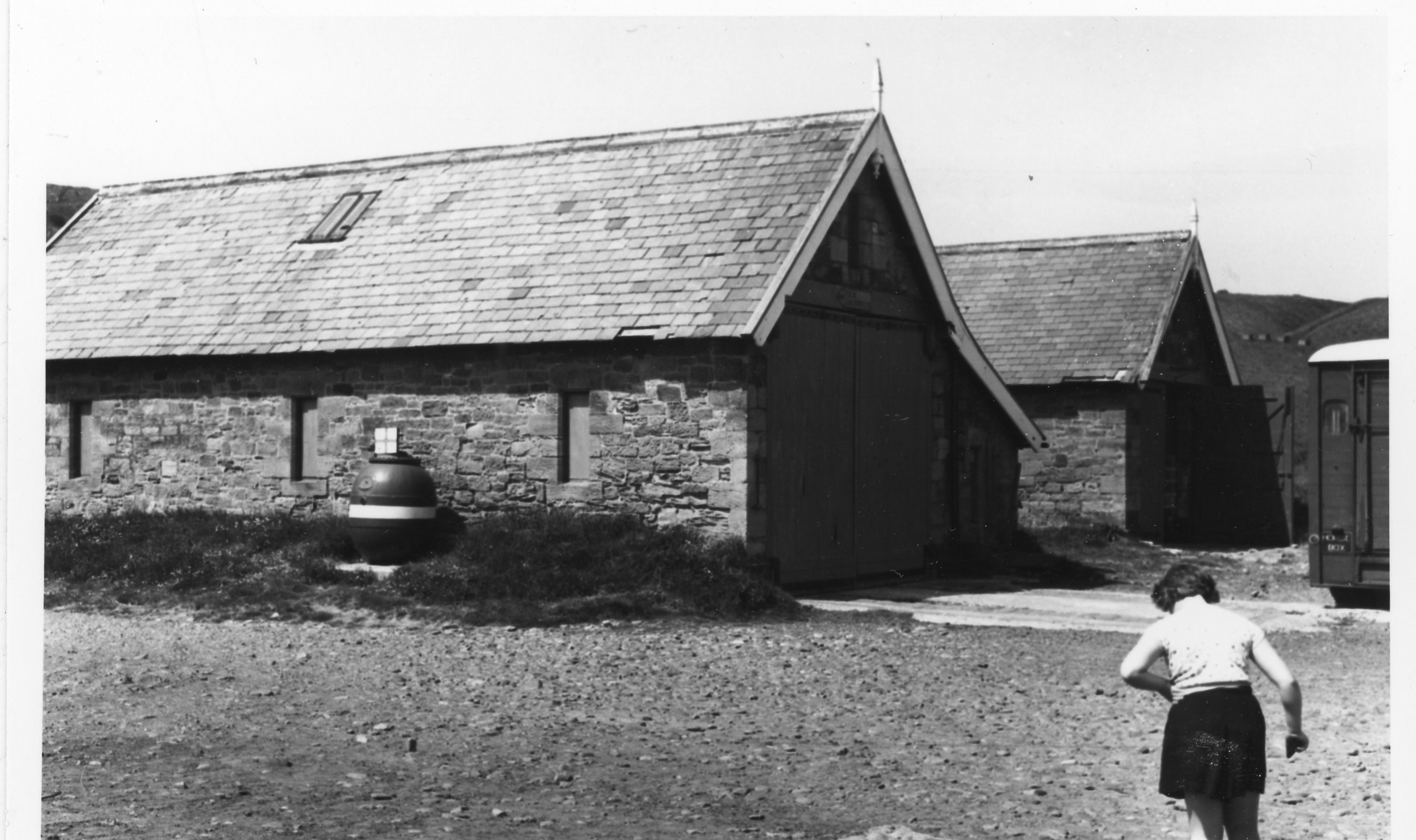 Two lifeboat buildings with small child running in front