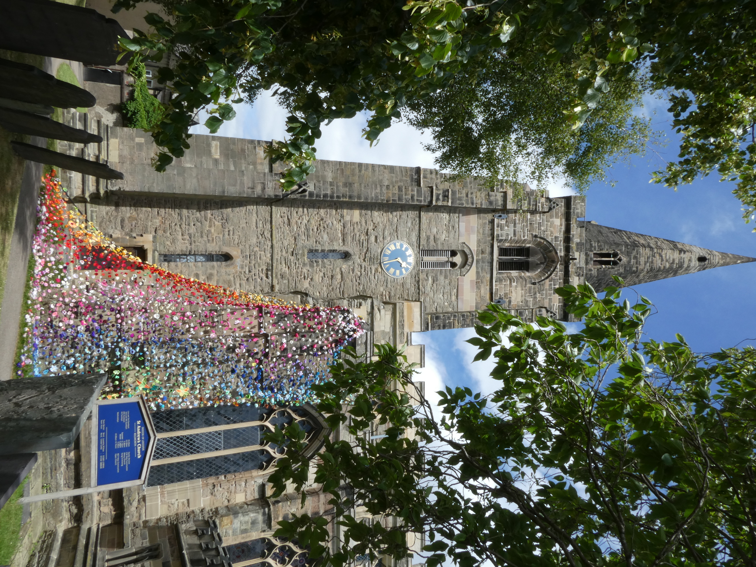 The tower of St Andrew's Church; with the corner of the south aisle decorated with knitted & crochet flowers.