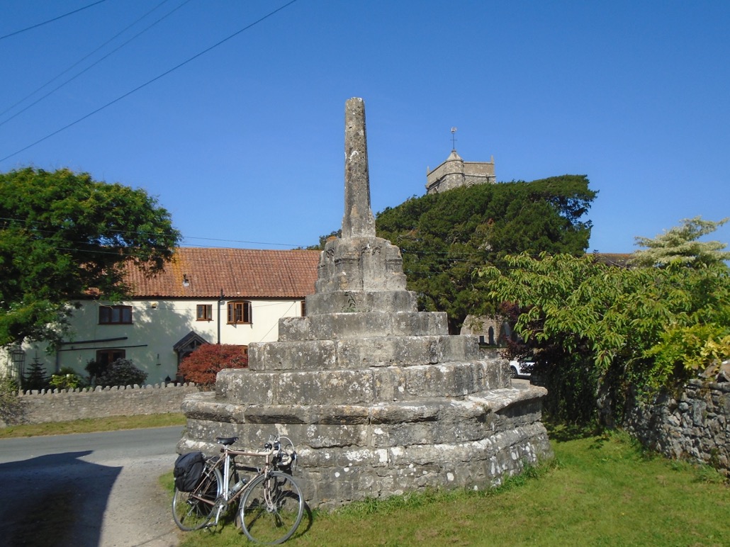 The cross base as seen in September 2022, with a bicycle emphasising the unusual height and impressive bulk of the base.