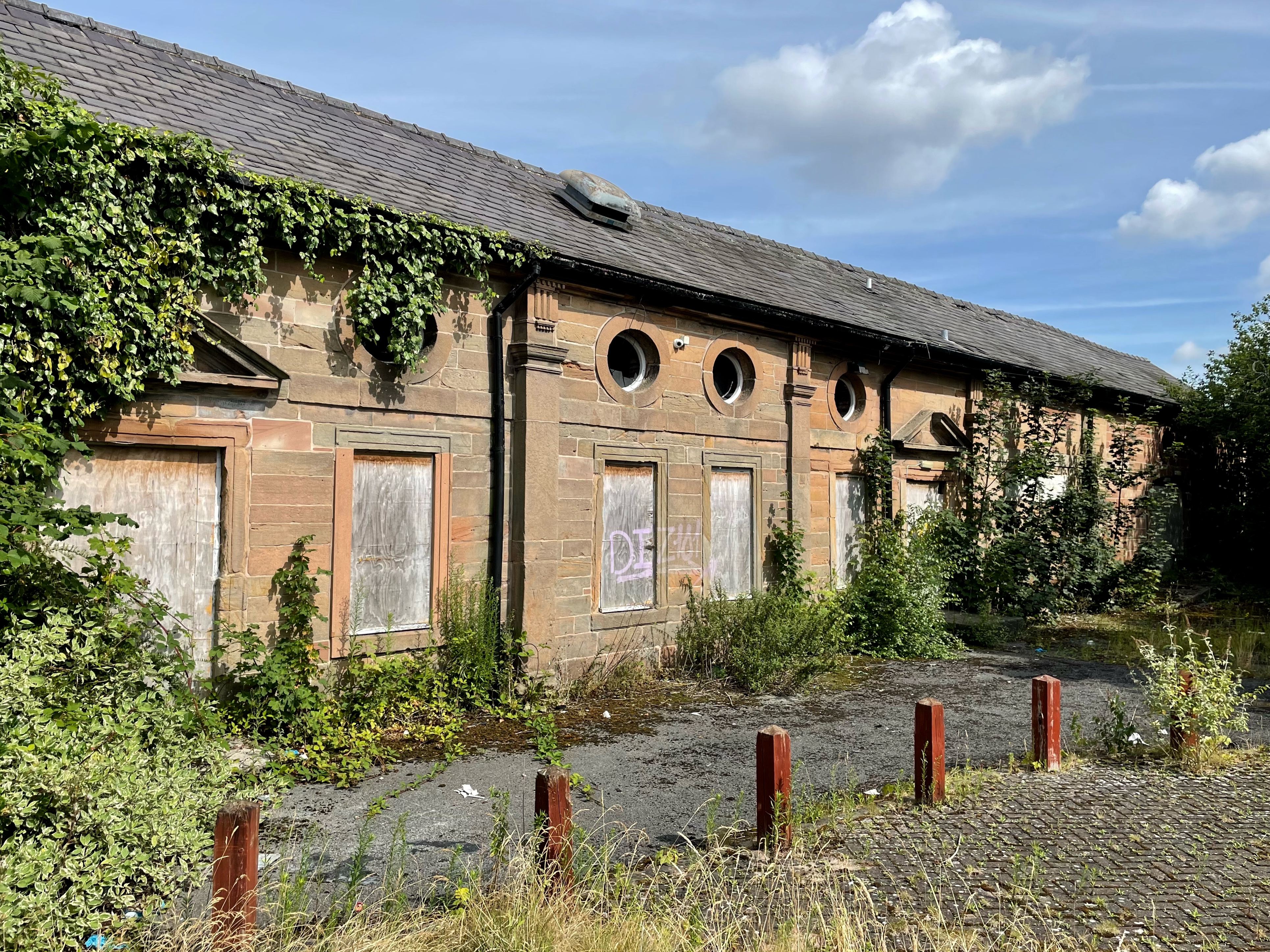 General view of east facade showing considerable encroachment of vegetation 