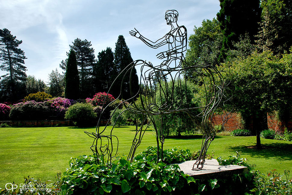 Garden at Hare Hill, Cheshire - large expanse of manicured lawn with horse and rider sculpture in the foreground. 