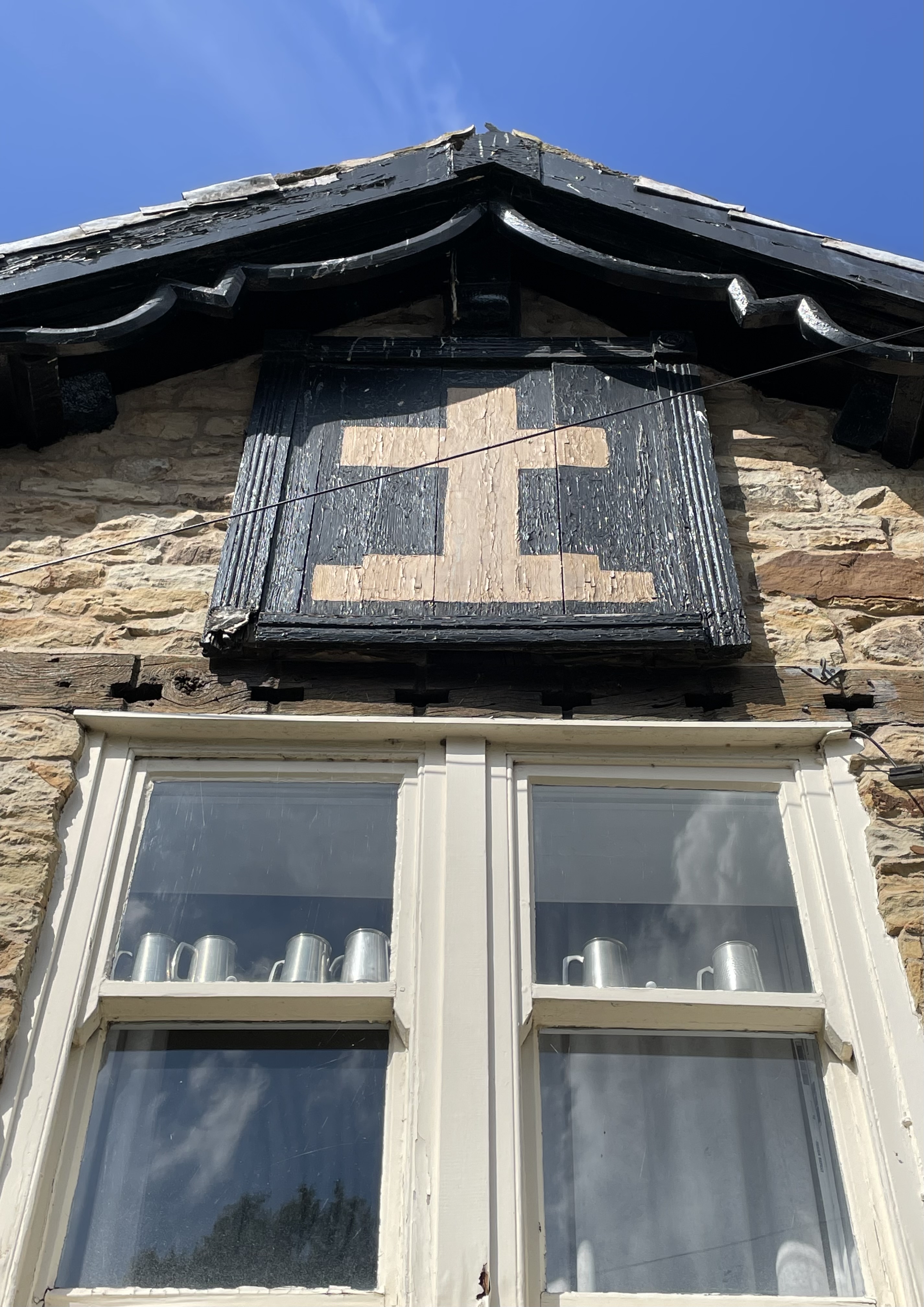 Golden Cross board above gable window.