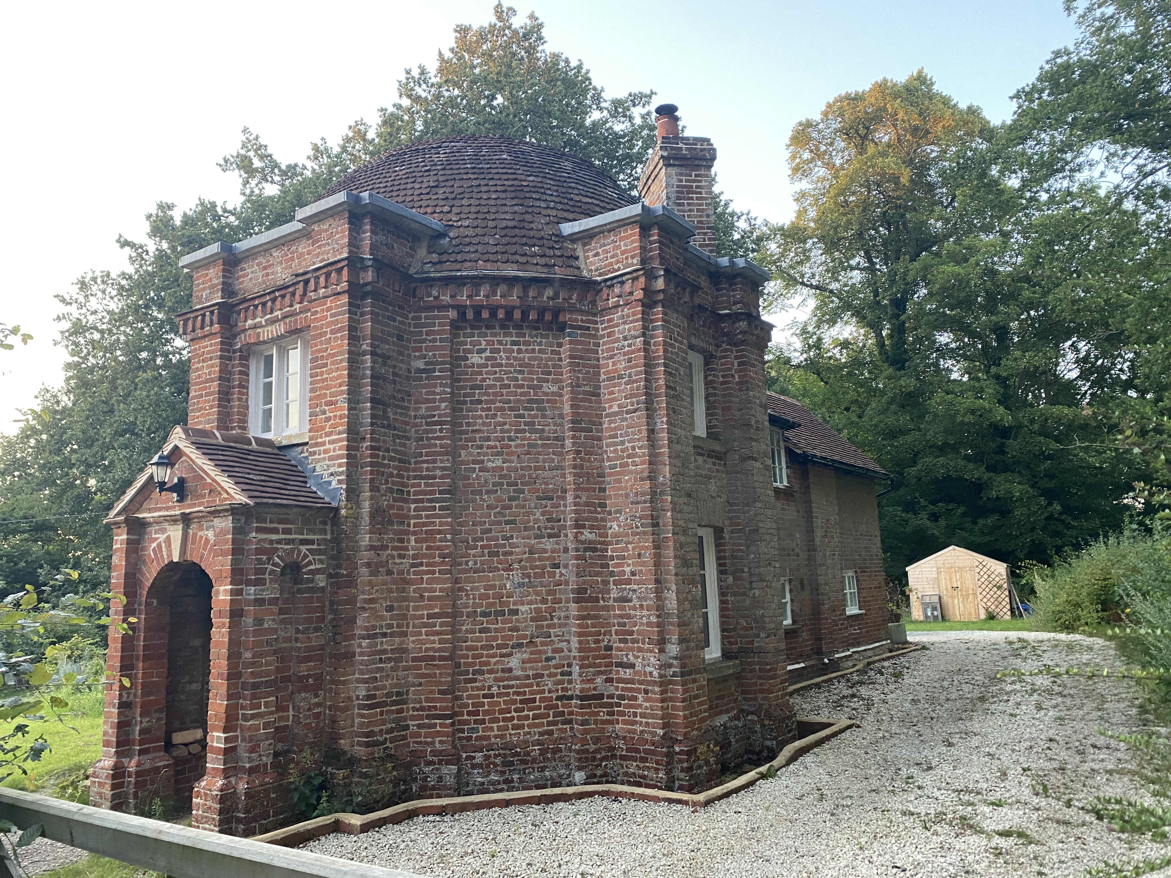 A small building with red brick, a domed brick roof and small single Pane glass windows 