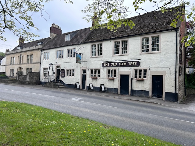 A public house which is painted white, situated on the side of a road.
