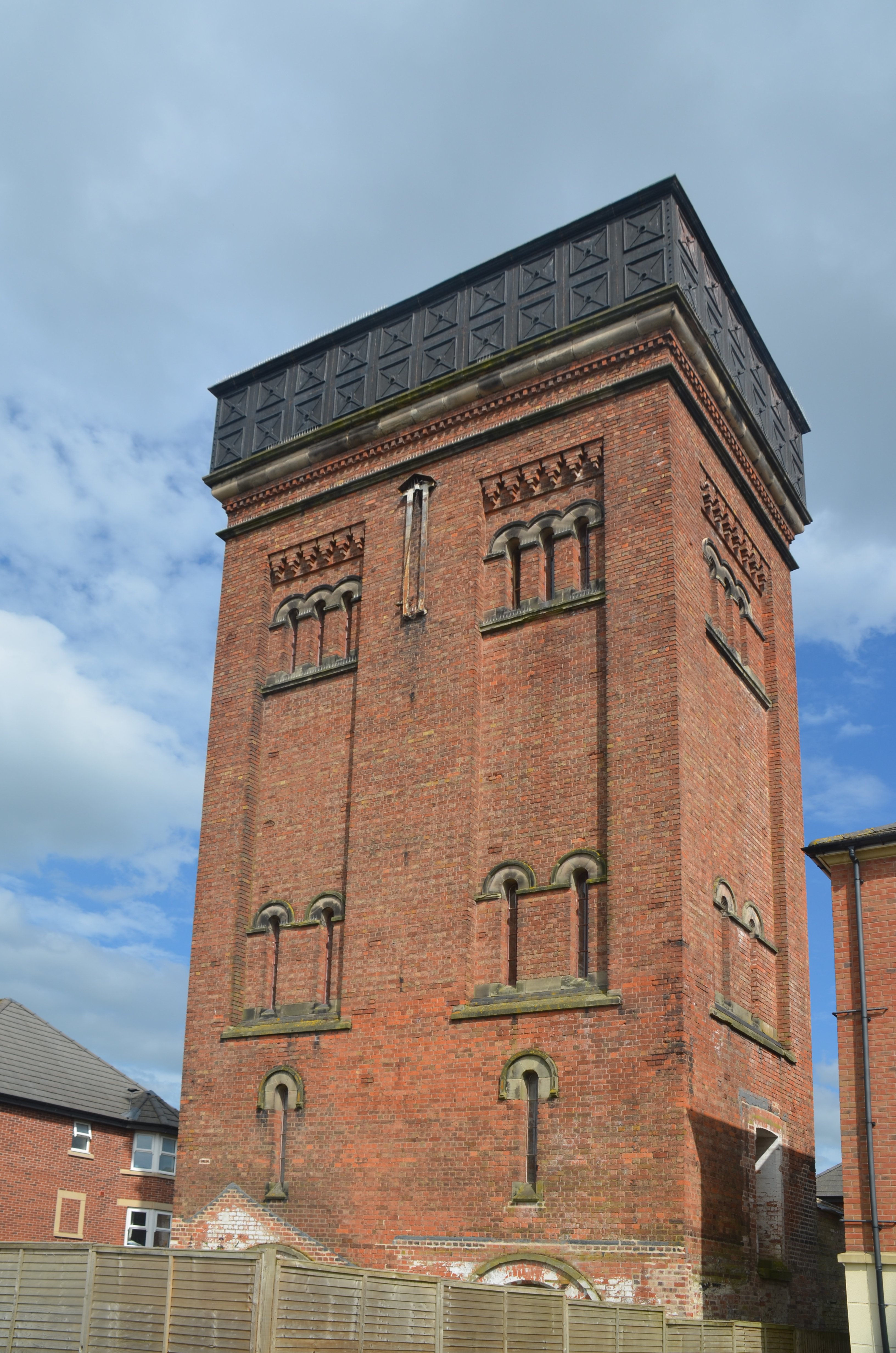 The photo is taken from ground level and shows a brick-built tower with a water tank on top.