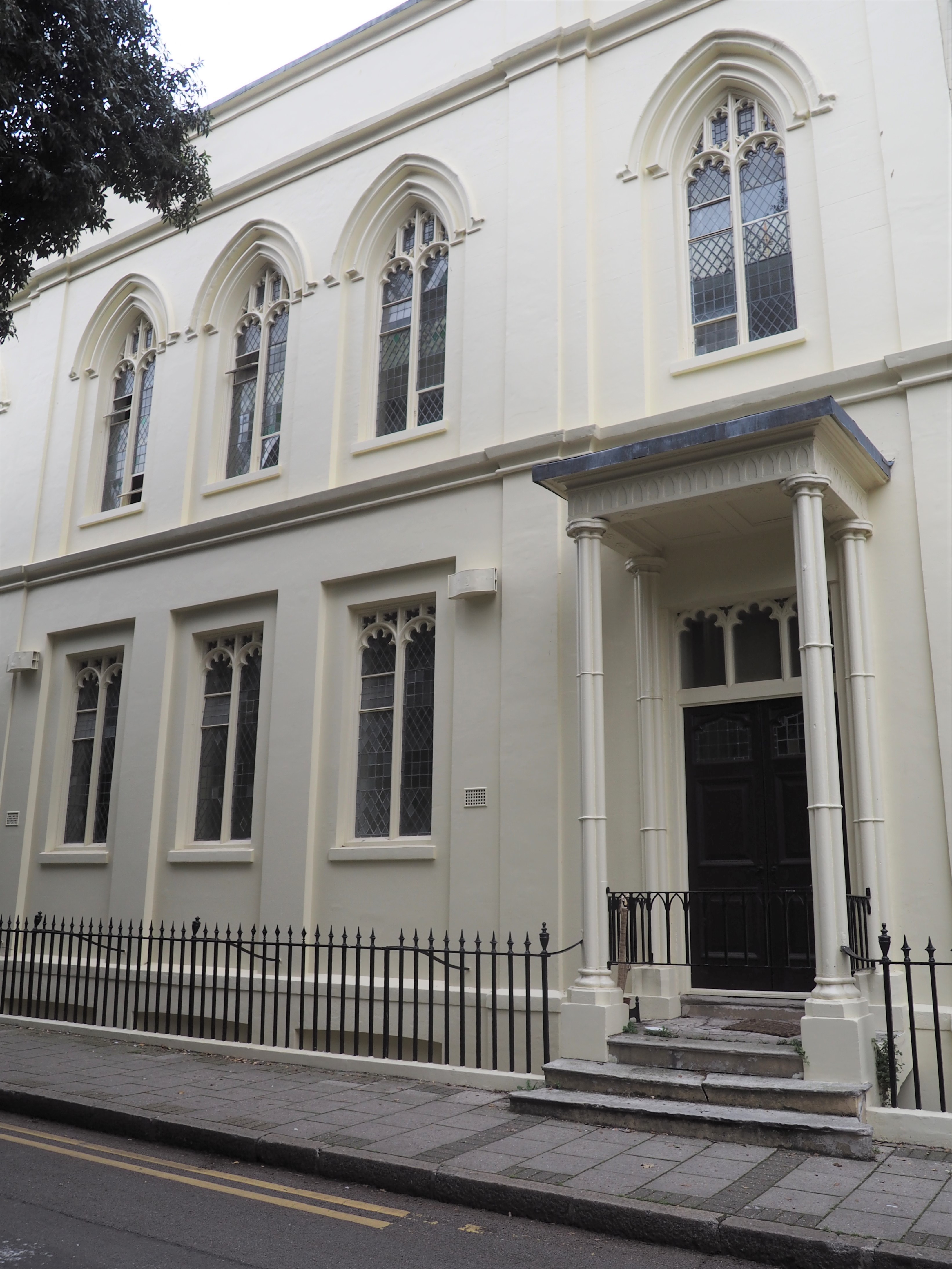 White stuccoed classical front of former 2 storey chapel. Gothic style windows 1st floor. Door with porch & pillars