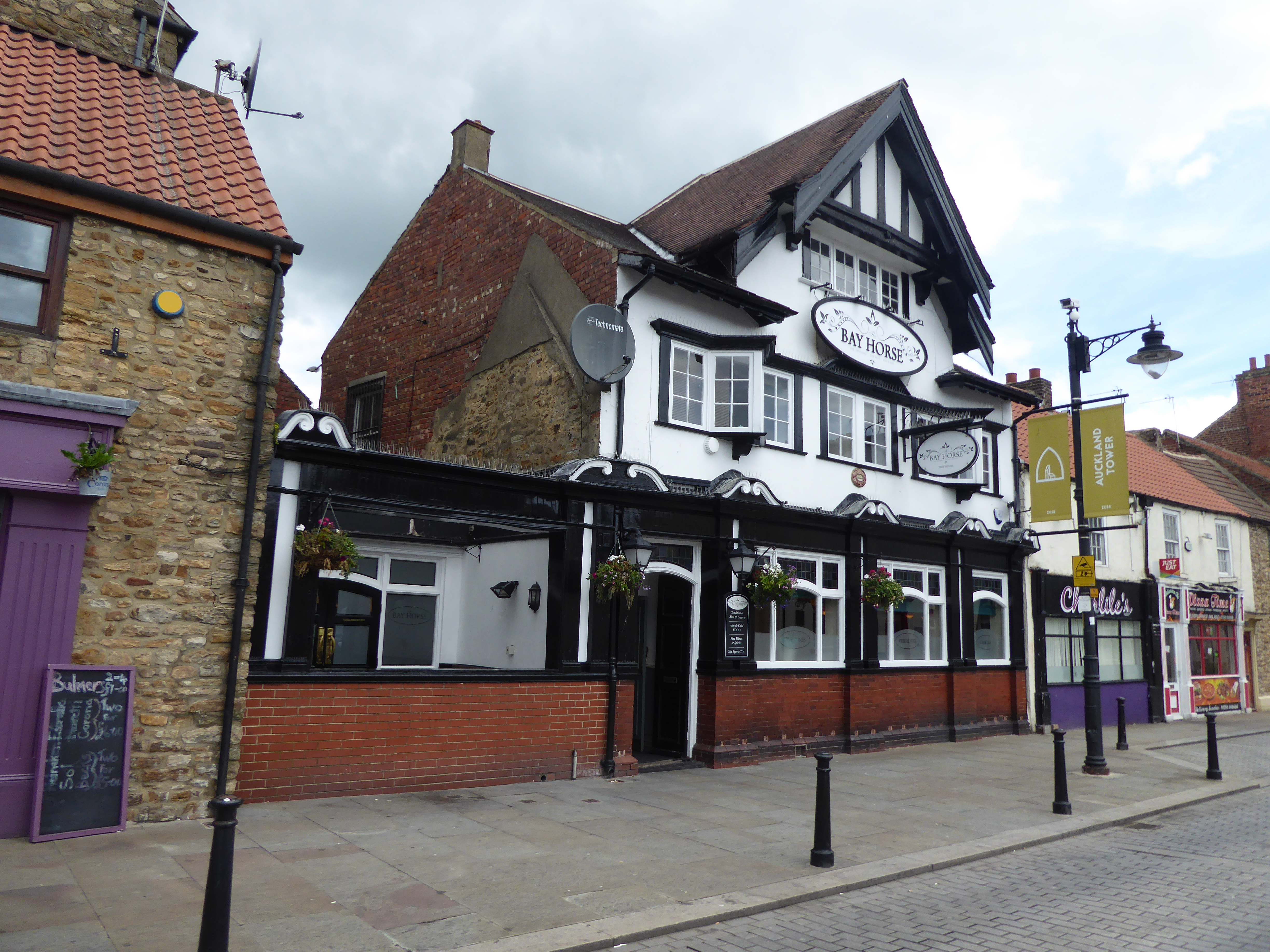 Three-storey building with mock-timber frame to front gable. Brick to ground floor. Pitched roof. 