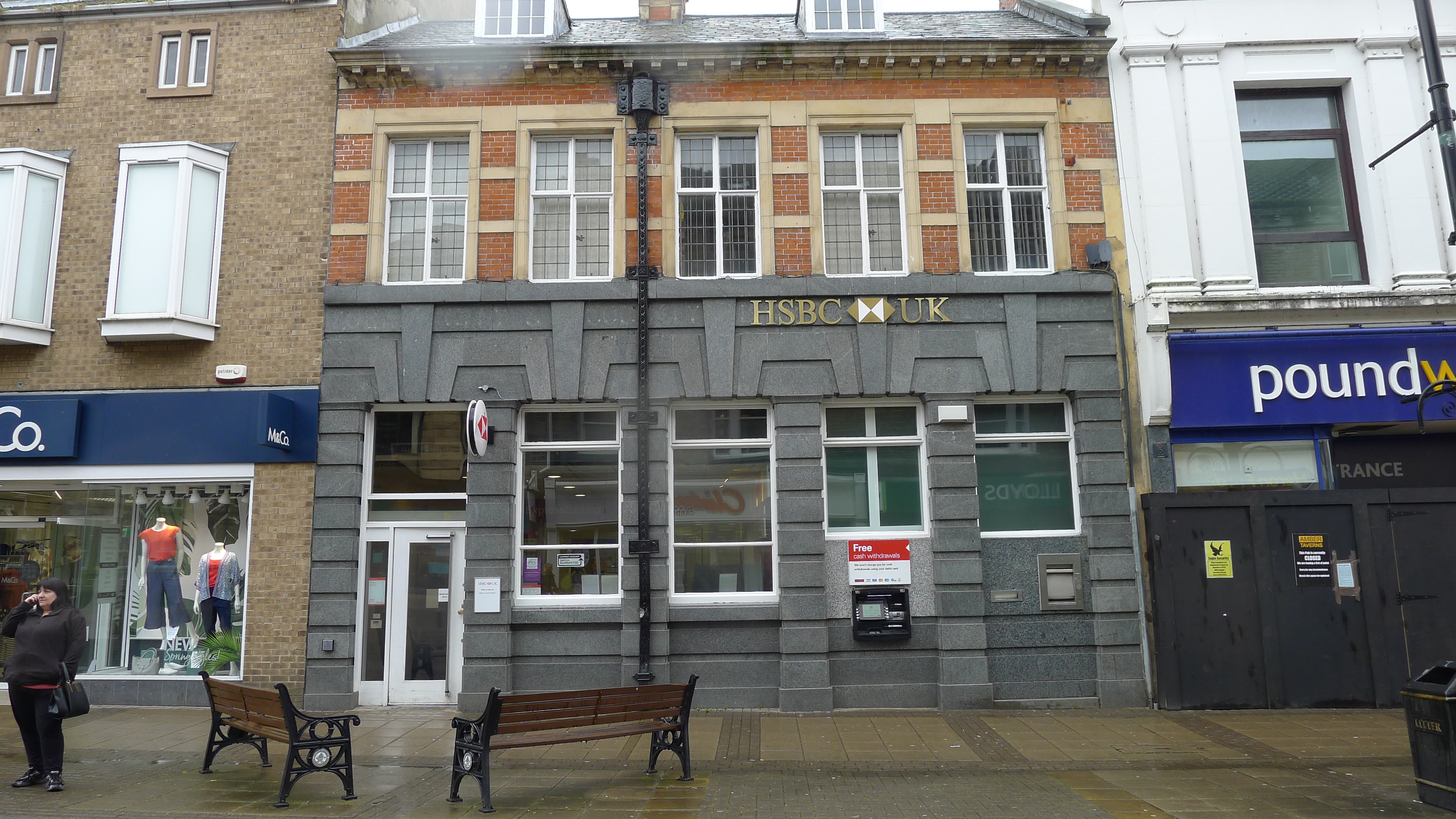 Two-storey building with grey granite to ground floor and red brick with stone dressings to first floor. Pitched roof.