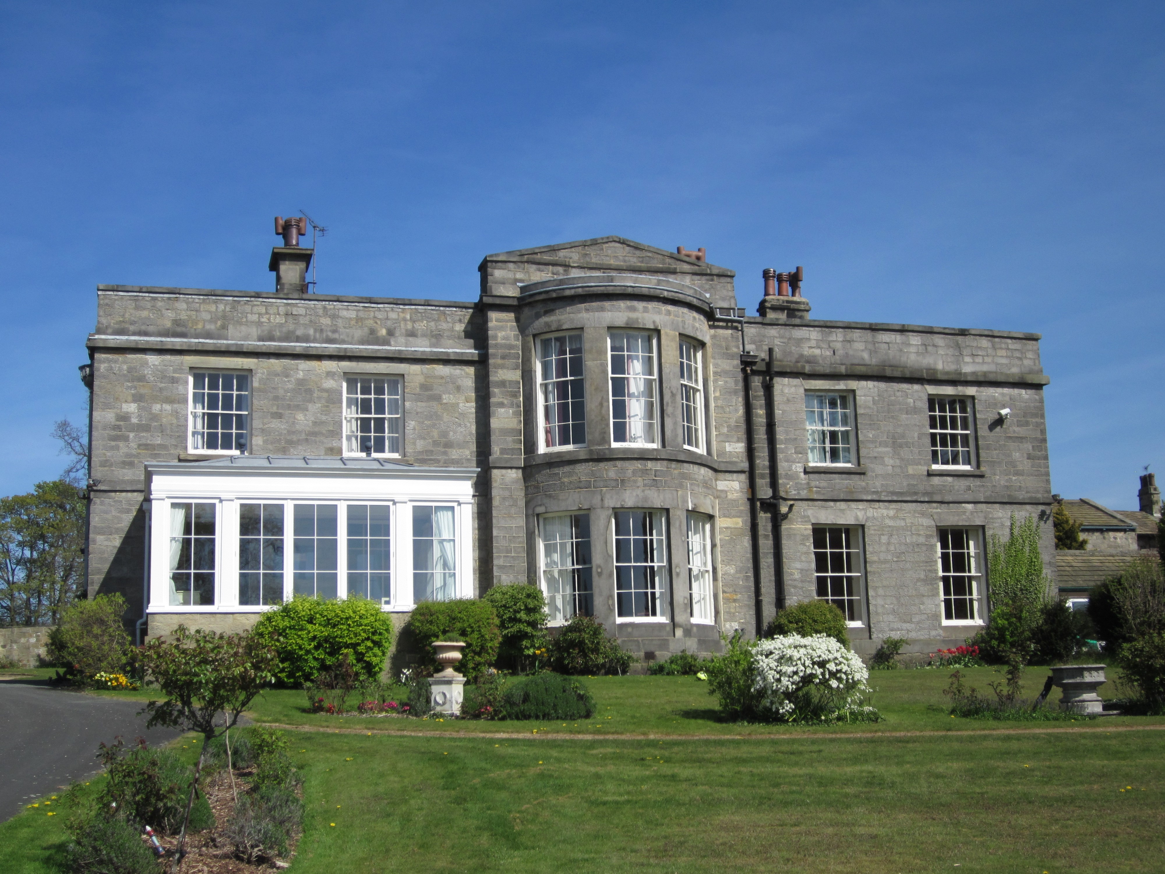 Stone two-storey mansion with central bowed windows.
