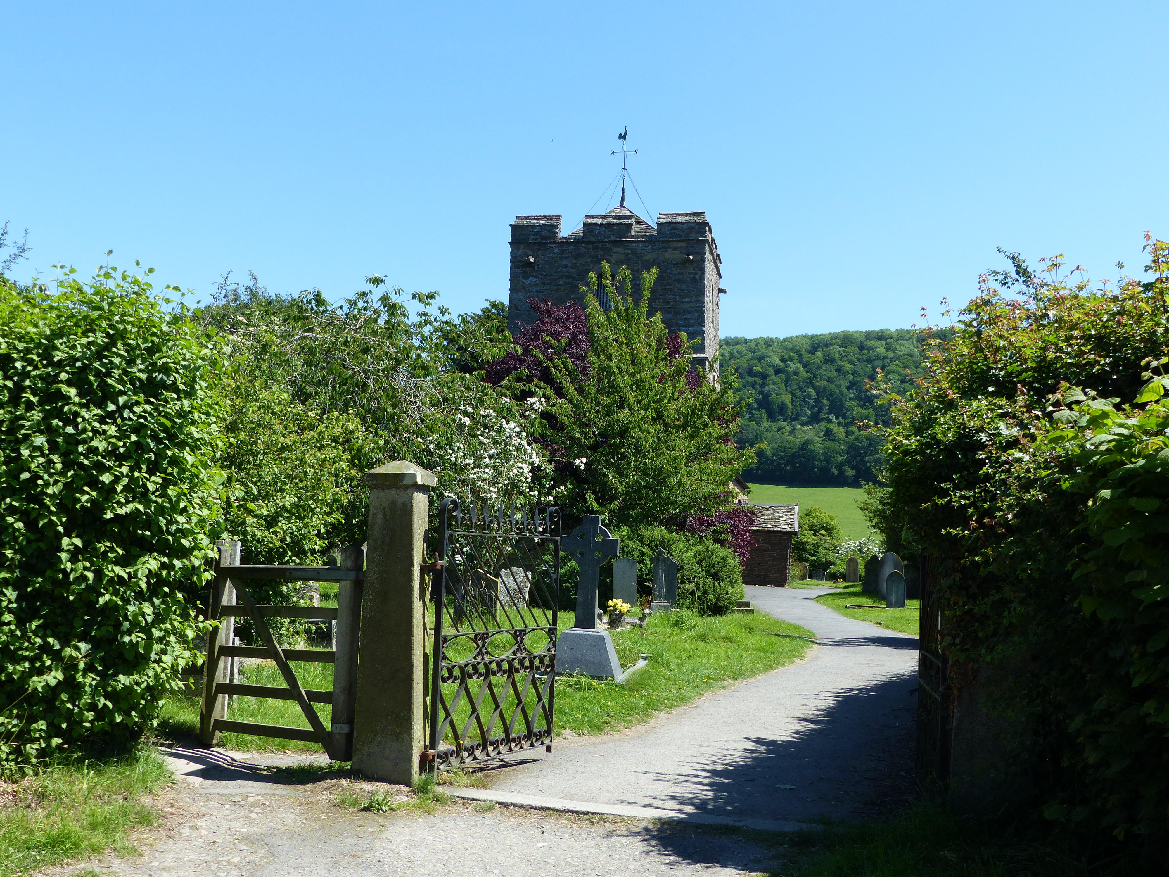 Stone gate pier with metal gates and church in background.