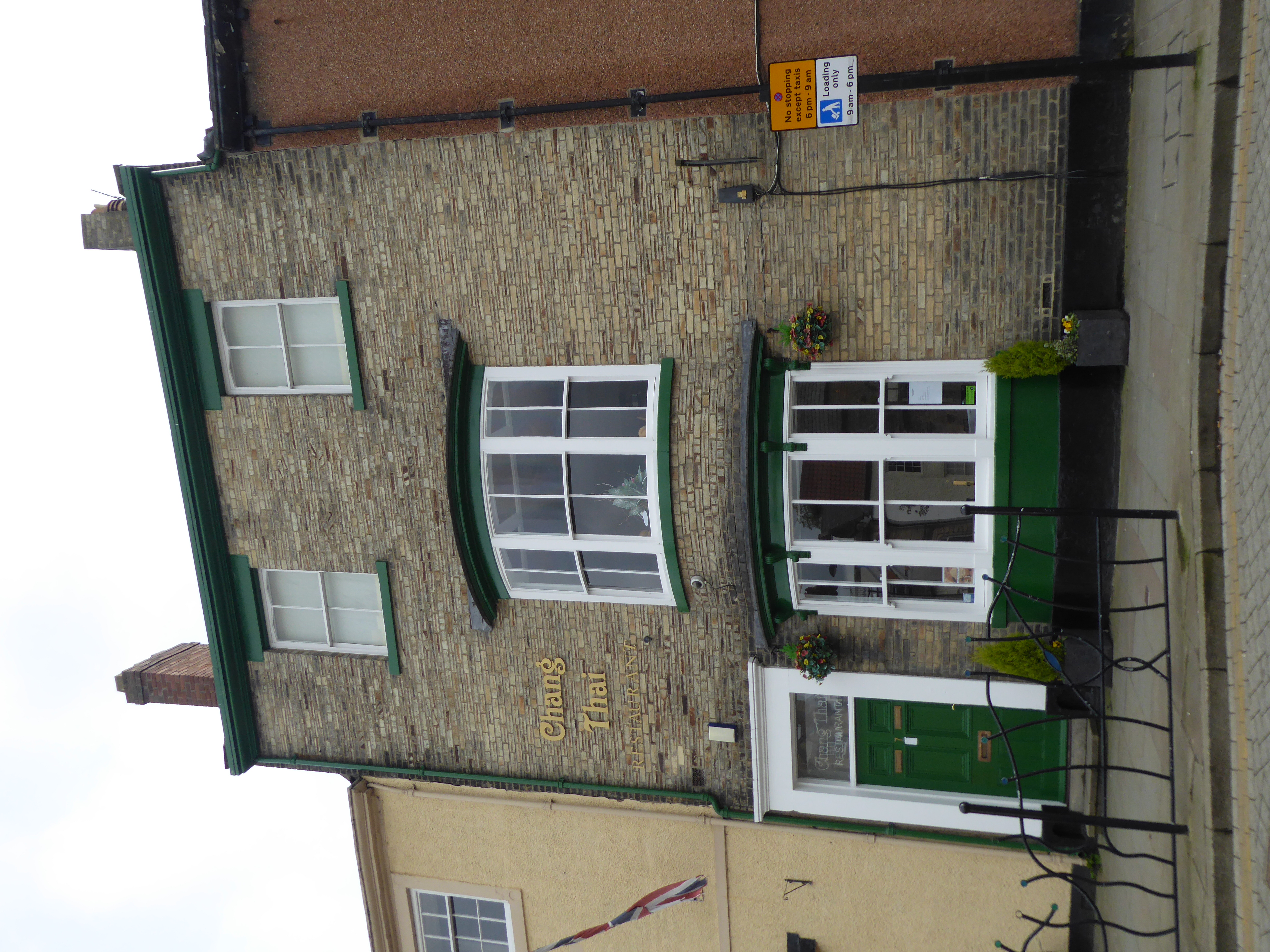 A three-storey yellow-brick building with pitched roof and chimney stacks.