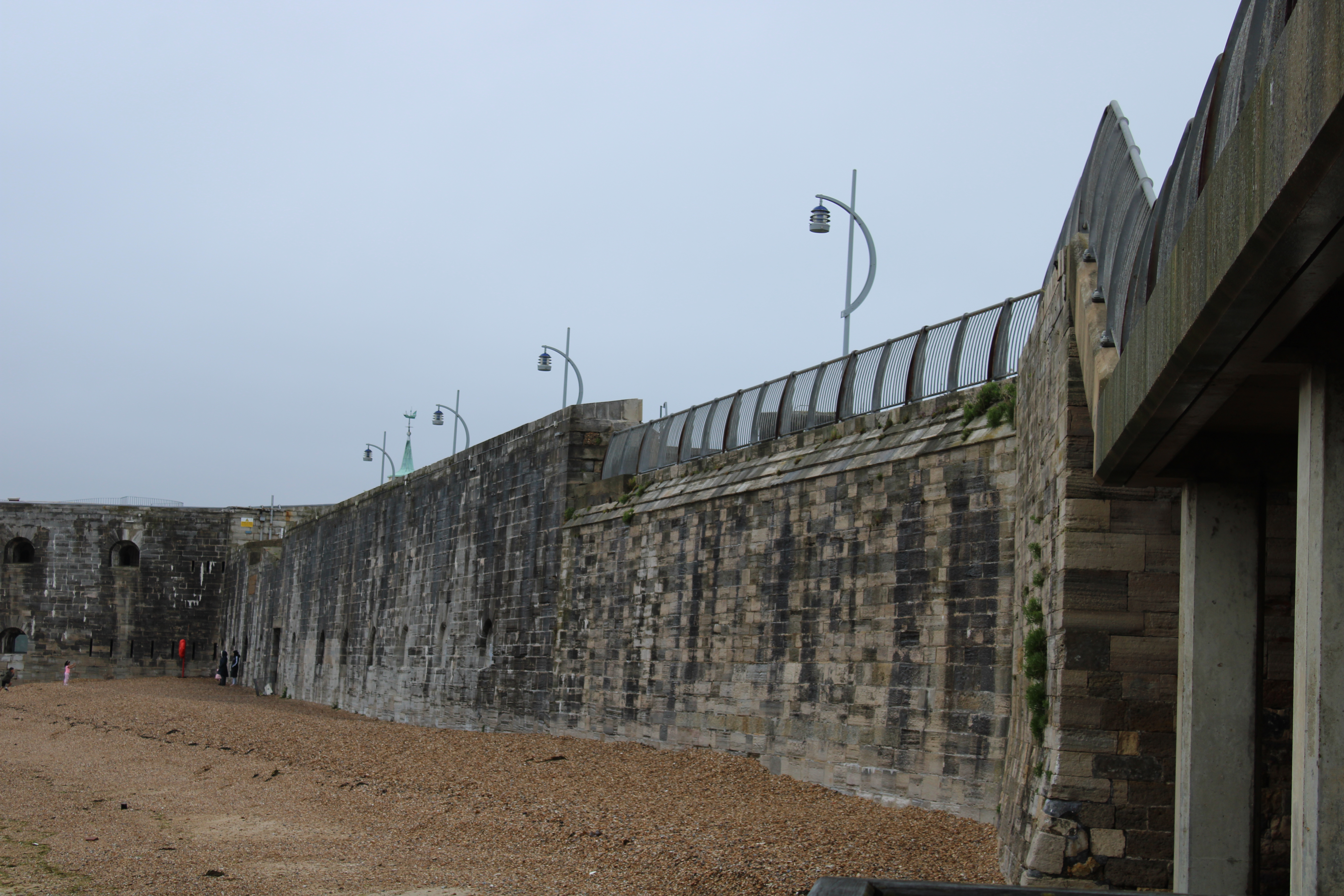 The Battery from the seaward side showing a section of shingle beach, the walls and modern lighting on the upper walkway