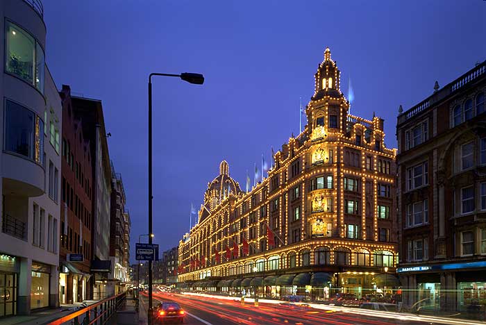 SALE Harrods winter sales lights sunset department store lit up at dusk  with lit 'Sale' sign shoppers speed blurred red bus and passing taxis on  red route Brompton Road Knightsbridge London SW1