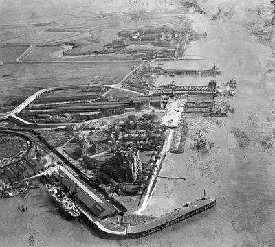 The Tilbury Hotel, railway station and waterfront, with Tilbury Fort in the distance, Tilbury, 1928. This image has been produced from a damaged negative.