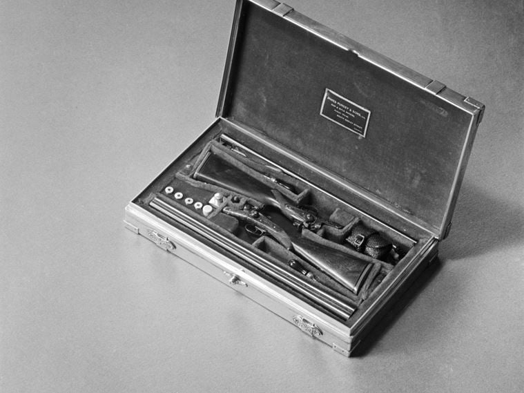 A view of a case containing two minature long barrelled guns made by James Purdey and Sons of London