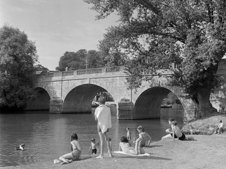 General view of Wallingford Bridge from the bank showing children in the water and on the bankside. It has 17 arches although only 5 actually span the river