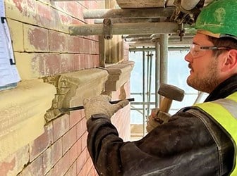 Apprentice Matthew Tinsley removes old masonry from a historic building.