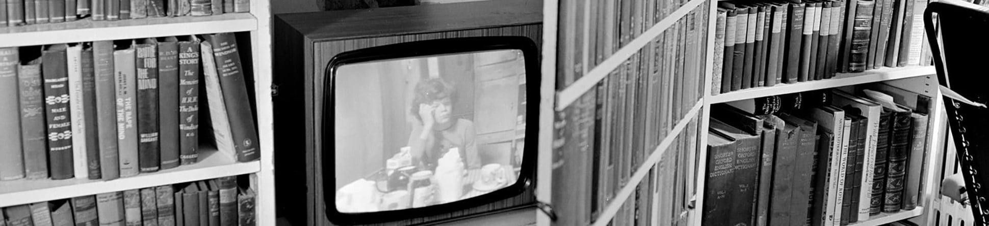 Black and white photo of a television in a bookcase