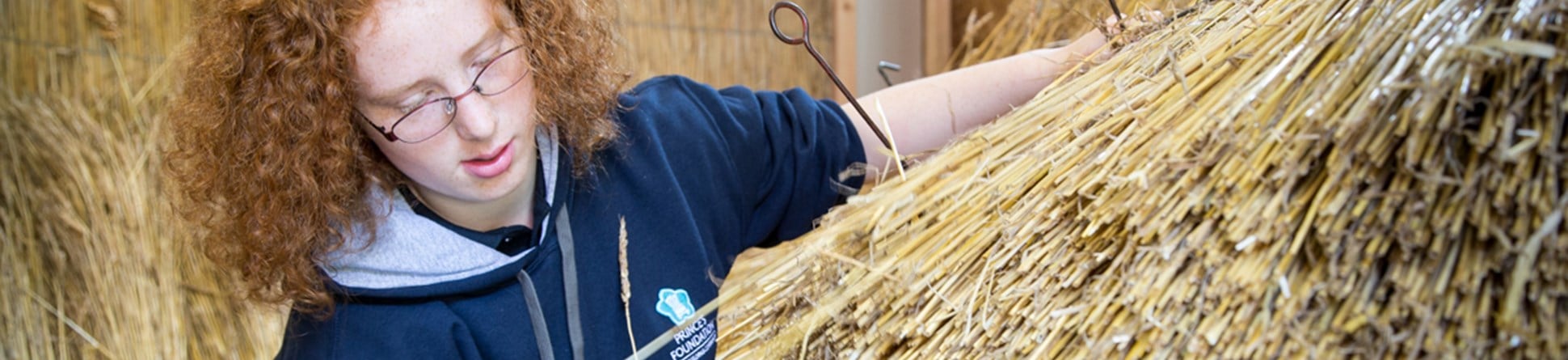 An image of King's Foundation trainee Miriam Johnson, learning traditional methods of thatching, as part of her bursary placement on the Building Craft Programme
