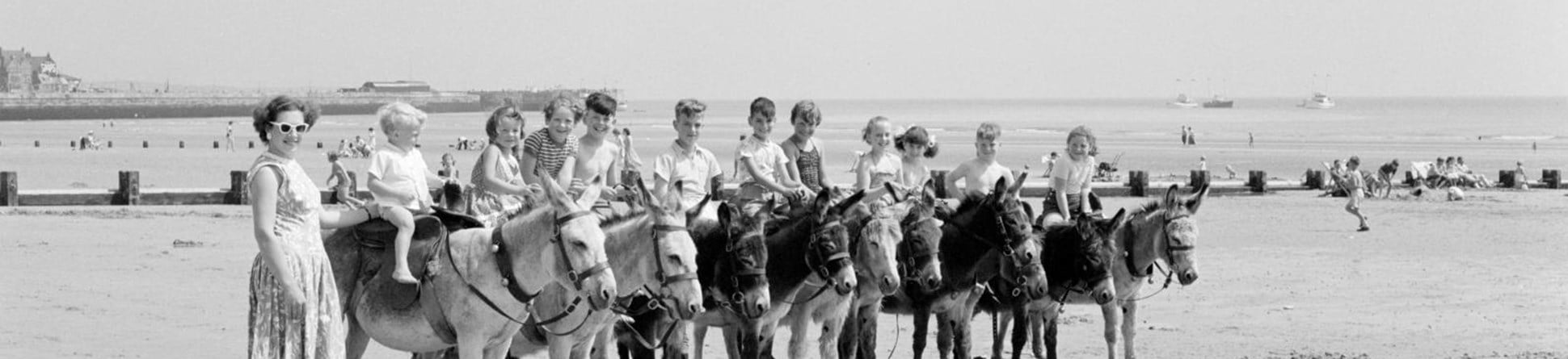 Children sitting on donkeys in a line on the beach at Bridlington