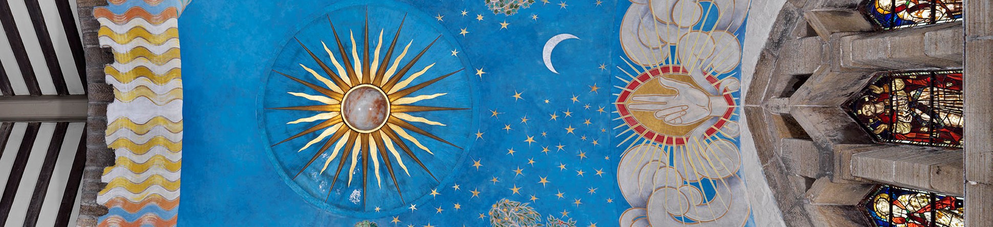 Church ceiling mural featuring sun, moon, stars, trees and a hand flanked by clouds, all against a bright blue background.