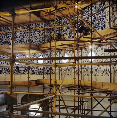Two men on intricate scaffolding complete tiling at the London Central Mosque.