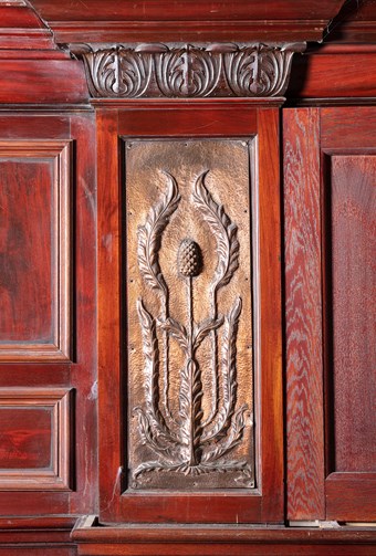 Detail of a public house interior with metal sheet decorated metal sheet depicting a thistle , wit surrounding hardwood panelling.
