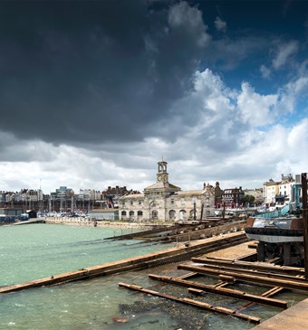 A view of Ramsgate harbour and clock house, with the sea lapping against the slipways