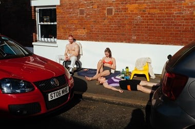A young man and two young women lounge on a hot London pavement on a summer's day