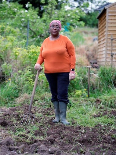 A woman posing with a gardening fork in an allotment.