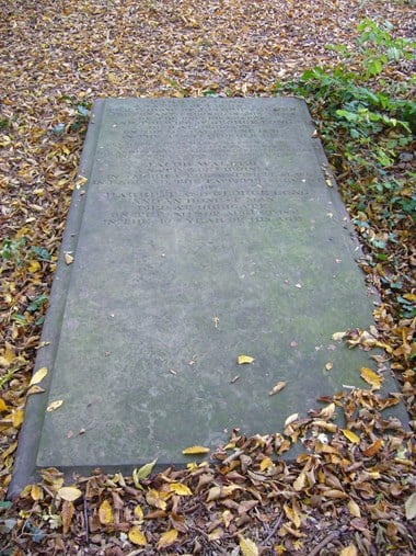 Large flat grey stone with moulded edge, seen from the bottom end, surrounded by autumn leaves. The inscriptions are at the top end of the stone, first the one for Harriet Long, then the one for Jacob Walker, who is described as ‘an honest man’.