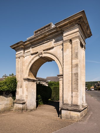 Freestanding stone archway. Arch flanked by coupled Doric pilasters, with cornice above. Between arch and cornice is a rectangular plaque, the inscription beginning Erected to commemorate the abolition of slavery. Behind, 20th-century housing.