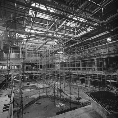 Black and white photograph showing the interior of Queensgate Shopping Centre, with a vast network of scaffolding in place.