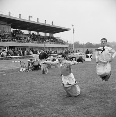 Two men jumping towards the finishing line of the men's sack race