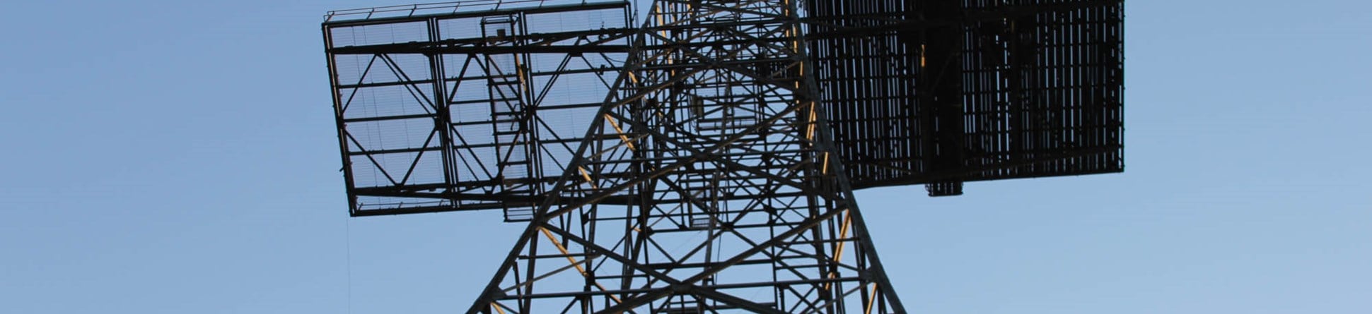 The metal structure of the Chain Home Tower rising into the blue sky