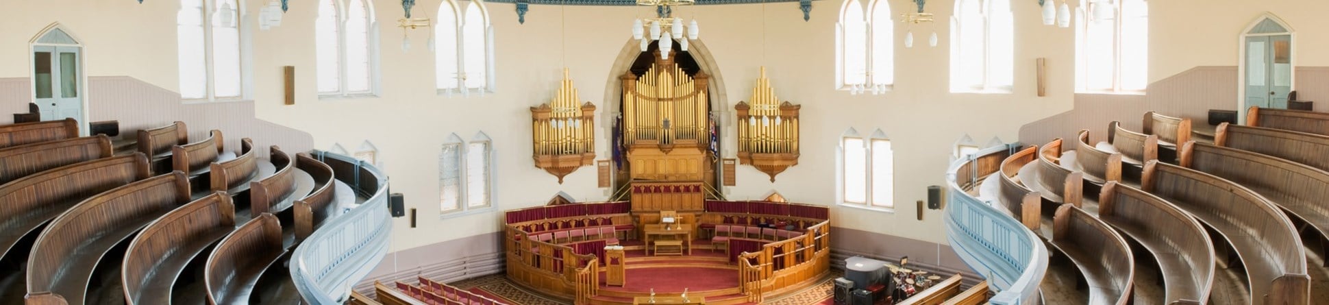 Interior, first floor, showing curved pews on first floor, straight pews on ground floor with organ pipes and central pulpit.