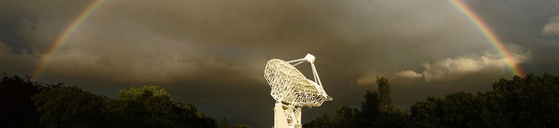 The Mark II Telescope at Jodrell Bank photographed against a moody sky encircled by a rainbow