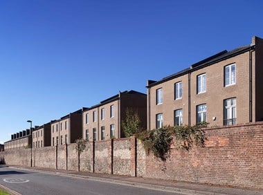 An exterior view of a boundary wall and redeveloped blocks of brick housing.