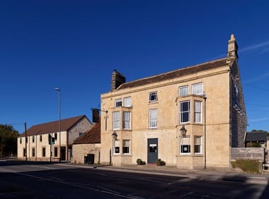 A three storey historic stone-built inn with a modern two storey gabled building adjacent.