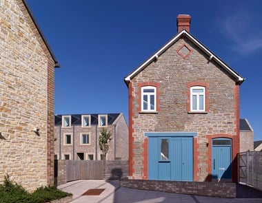 A two storey stone outbuilding with brick quoins and detailing now in use as a dwelling.