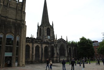 Image of the exterior South side of Sheffield Cathedral focussing on the landscaping round the building, which is a public space.